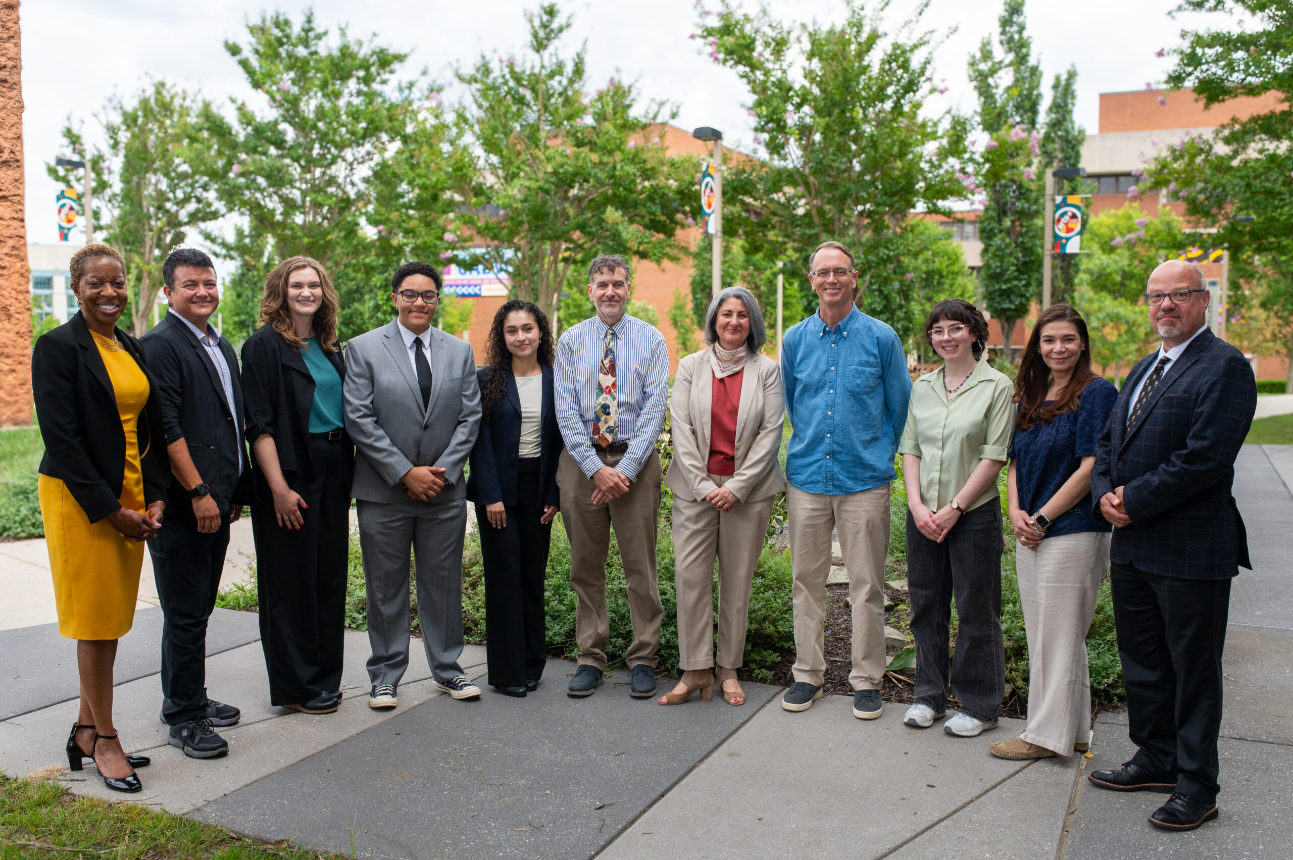 Nine USC members standing outside in a semicircle with President Sheares Ashby on left end and Provost van Dulmen on the right end.